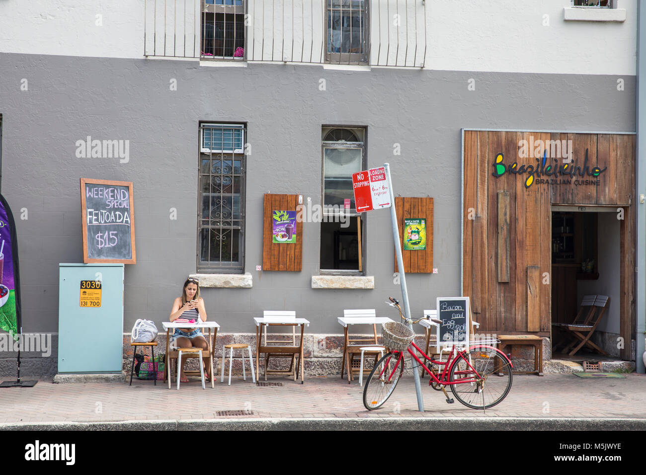 Femme assise seule au restaurant brésilien à Manly Beach, Sydney, Australie Banque D'Images