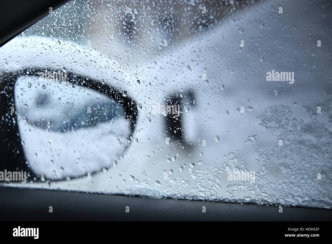 Goutte d'eau sur une fenêtre de voiture close-up. La conduite dangereuse dans de mauvaises conditions météorologiques. Temps de pluie à l'extérieur de voiture. Banque D'Images