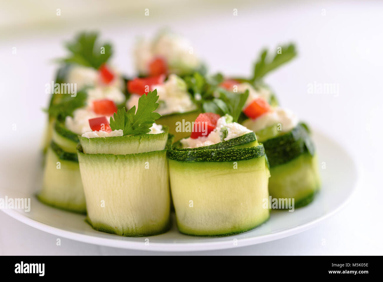 Rouleaux de courgettes farcies au fromage et ciboulette et paprika rouge. Banque D'Images