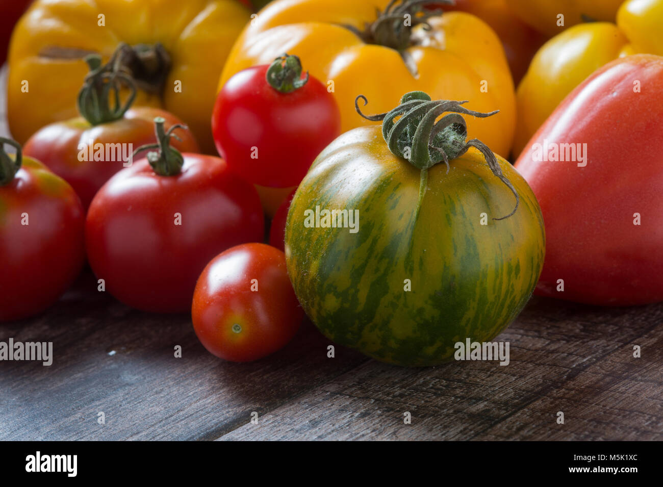 Tomates colorées sur fond de bois rustique. Banque D'Images
