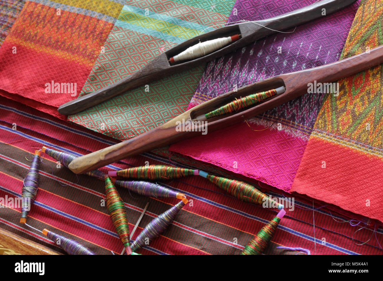 Bobines en bois colorés et de canette sur tissu de soie, le tissage traditionnel de la soie thaïlandaise Banque D'Images