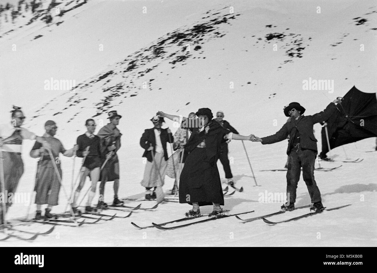 Le ski en Suisse en 1937. Un groupe de skieurs en robe de soirée sur les pistes de ski. Banque D'Images
