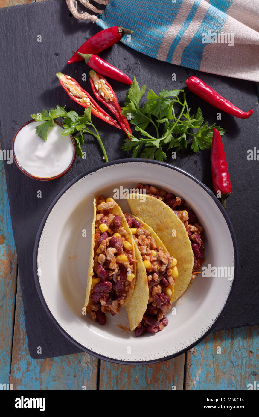 Trois tacos avec chili con carne dans un bol à côté du piment et persil frais Banque D'Images