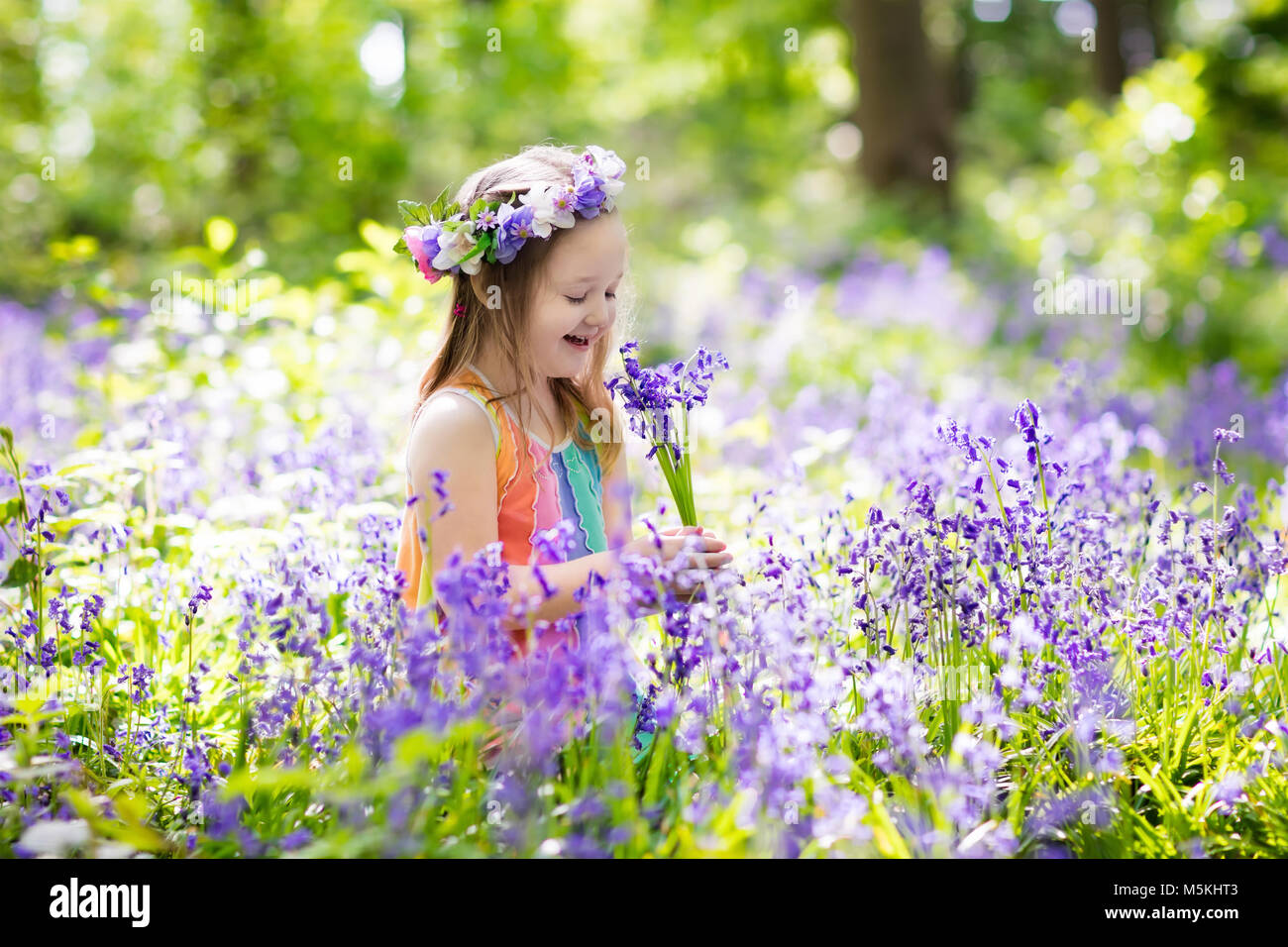 Kid en bois bluebell. Enfant avec des fleurs, des outils de jardin et de brouette. Girl gardening. Les enfants jouent en plein air bluebells, choisissez blue bell flower Banque D'Images