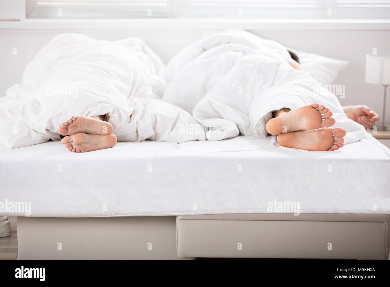 Photo de couple au lit sous les draps Banque D'Images