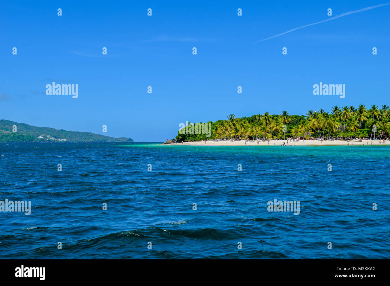 Belle plage avec des palmiers ciel bleu et l'eau turquoise, certains touristes s'amuser, se détendre et nager dans l'océan, la mer des Caraïbes Banque D'Images