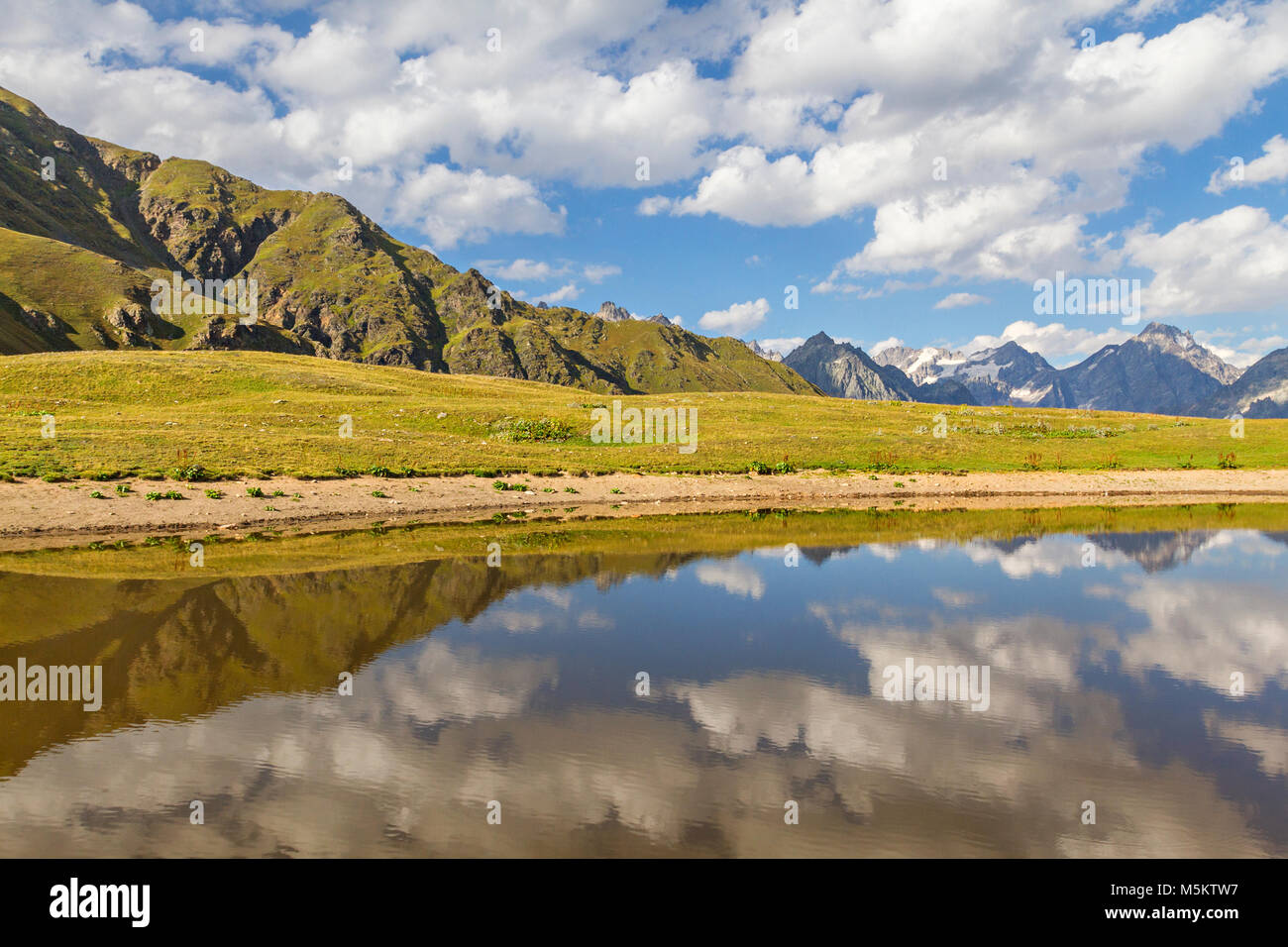 Réflexions de montagnes et nuages dans un lac de montagne, dans les montagnes du Caucase, en Géorgie. Banque D'Images