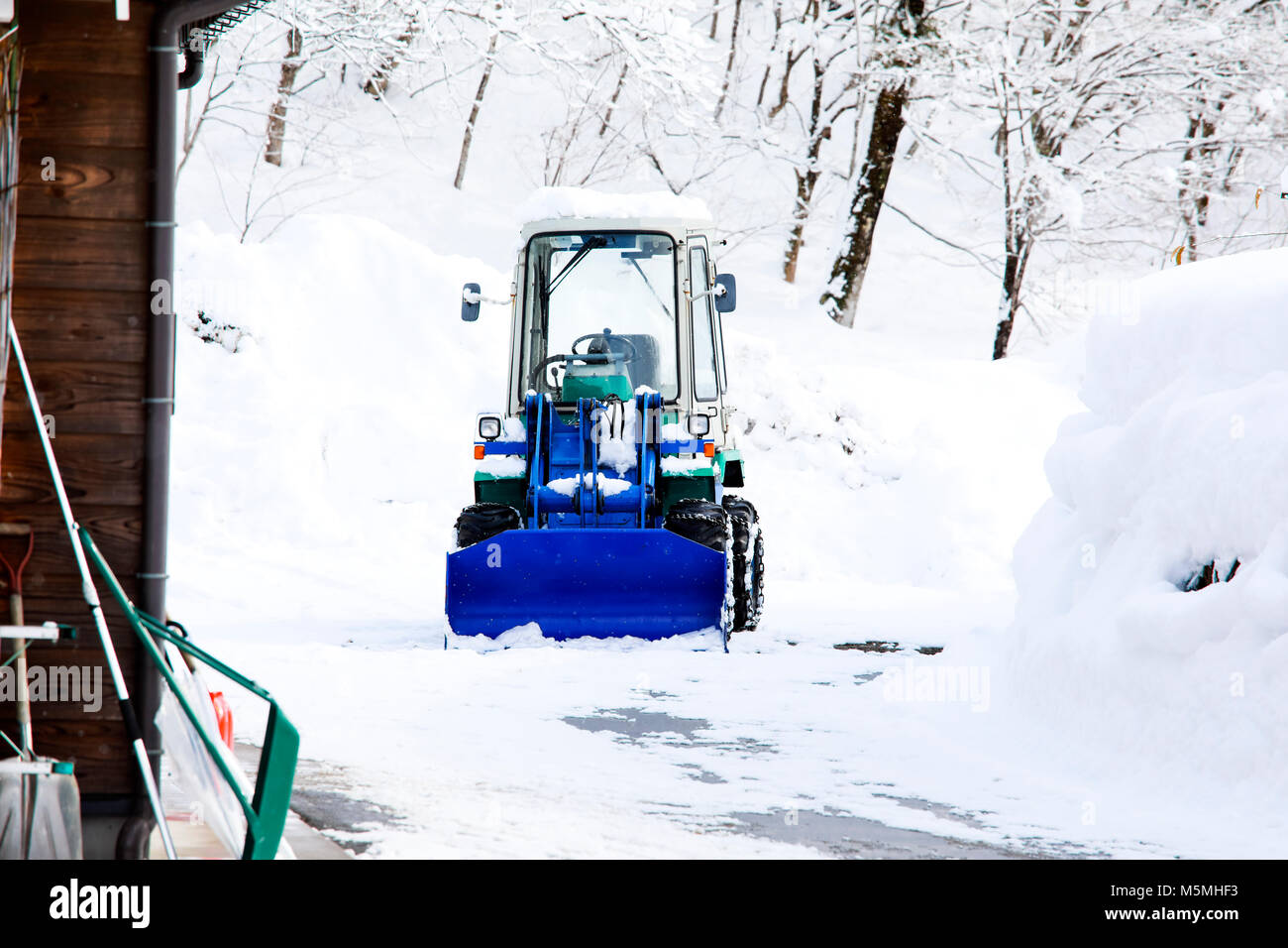 Le chargeur pour neige supprime neige sur la route dans le village Banque D'Images