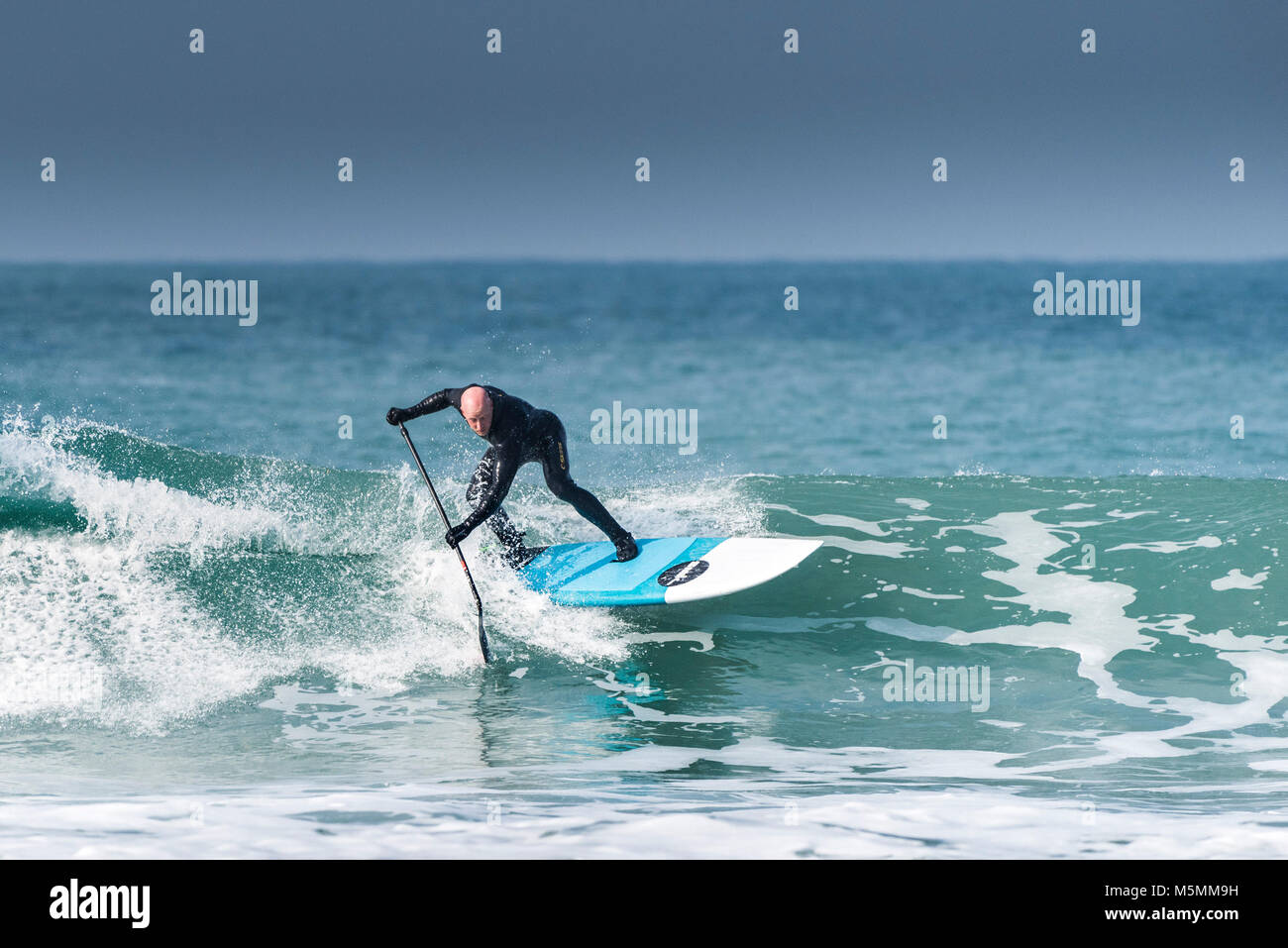 Une pagaie boarder une vague à dans Fistral Newquay, Cornwall. Banque D'Images