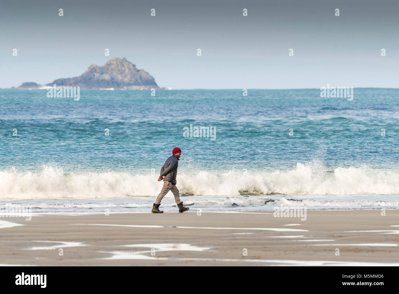Un homme bénéficiant d'une promenade le long du rivage à Sennen Cove, à Cornwall. Banque D'Images