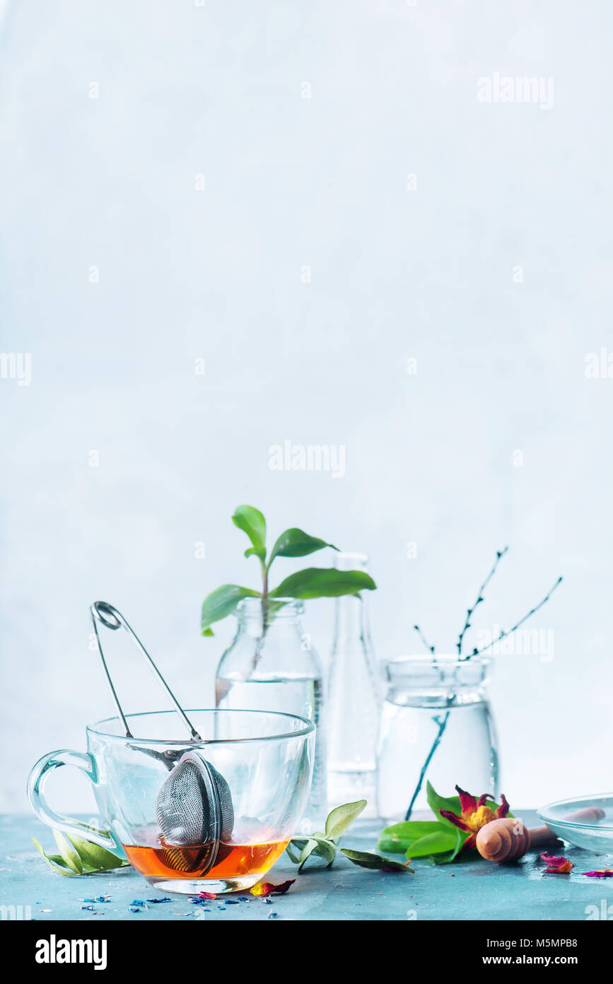 Tasse vide avec un tamis dans un ressort de la vie toujours avec des bouteilles en verre et feuilles vert frais sur un fond blanc. High-key spring still life with copy space. Banque D'Images Tasse vide avec un tamis dans un ressort de la vie toujours avec des bouteilles en verre et feuilles vert frais sur un fond blanc. High-key spring still life with copy space. Banque D'Images