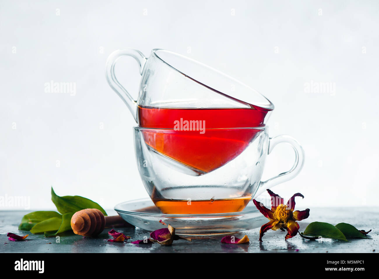 Pile de deux tasses de thé en verre sur un fond blanc avec une cuillère de miel vert frais, feuilles, fleurs et copiez l'espace. Tisane infusion concept. Banque D'Images Pile de deux tasses de thé en verre sur un fond blanc avec une cuillère de miel vert frais, feuilles, fleurs et copiez l'espace. Tisane infusion concept. Banque D'Images