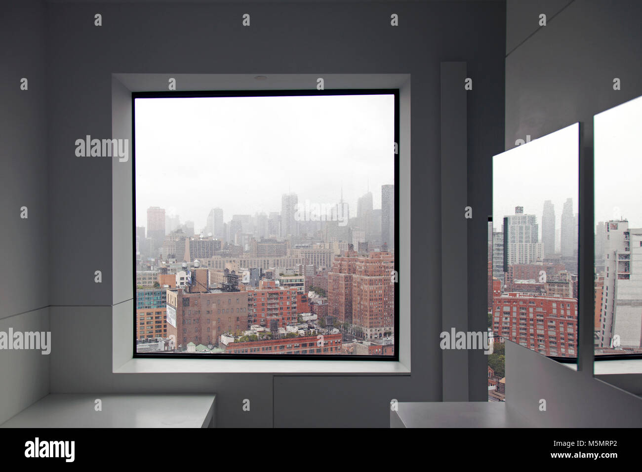 Une vue sur les toits de New York à partir d'une fenêtre et une réflexion de la ville sur le miroir à l'intérieur d'un appartement Banque D'Images