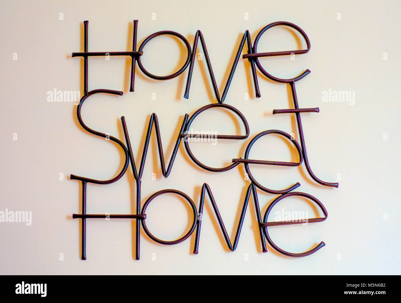 La devise "familier de Home Sweet Home", formé à partir de metal lettrage et apposée sur un mur intérieur de la maison. Angleterre, Royaume-Uni. Banque D'Images