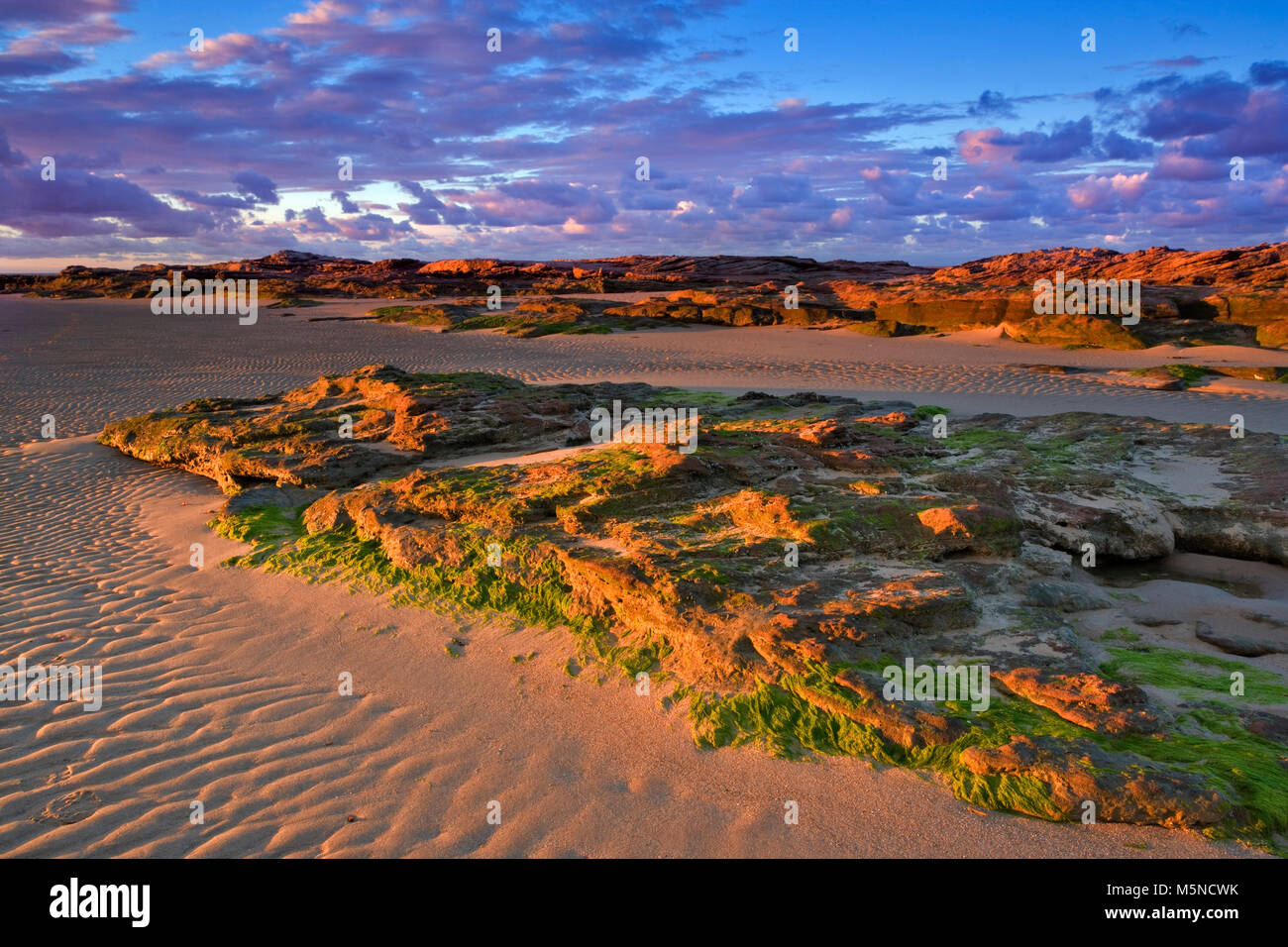 Coucher de soleil sur la craggy Roches Rouges de Hoylake Wirral, plage, en Angleterre. Banque D'Images