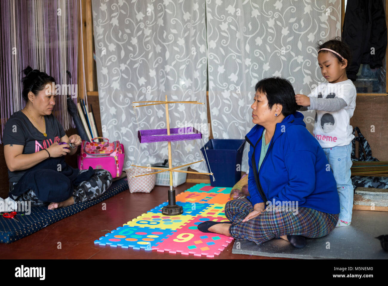 Thimphu, Bhoutan. Petite fille jouant avec les cheveux de sa mère. Banque D'Images