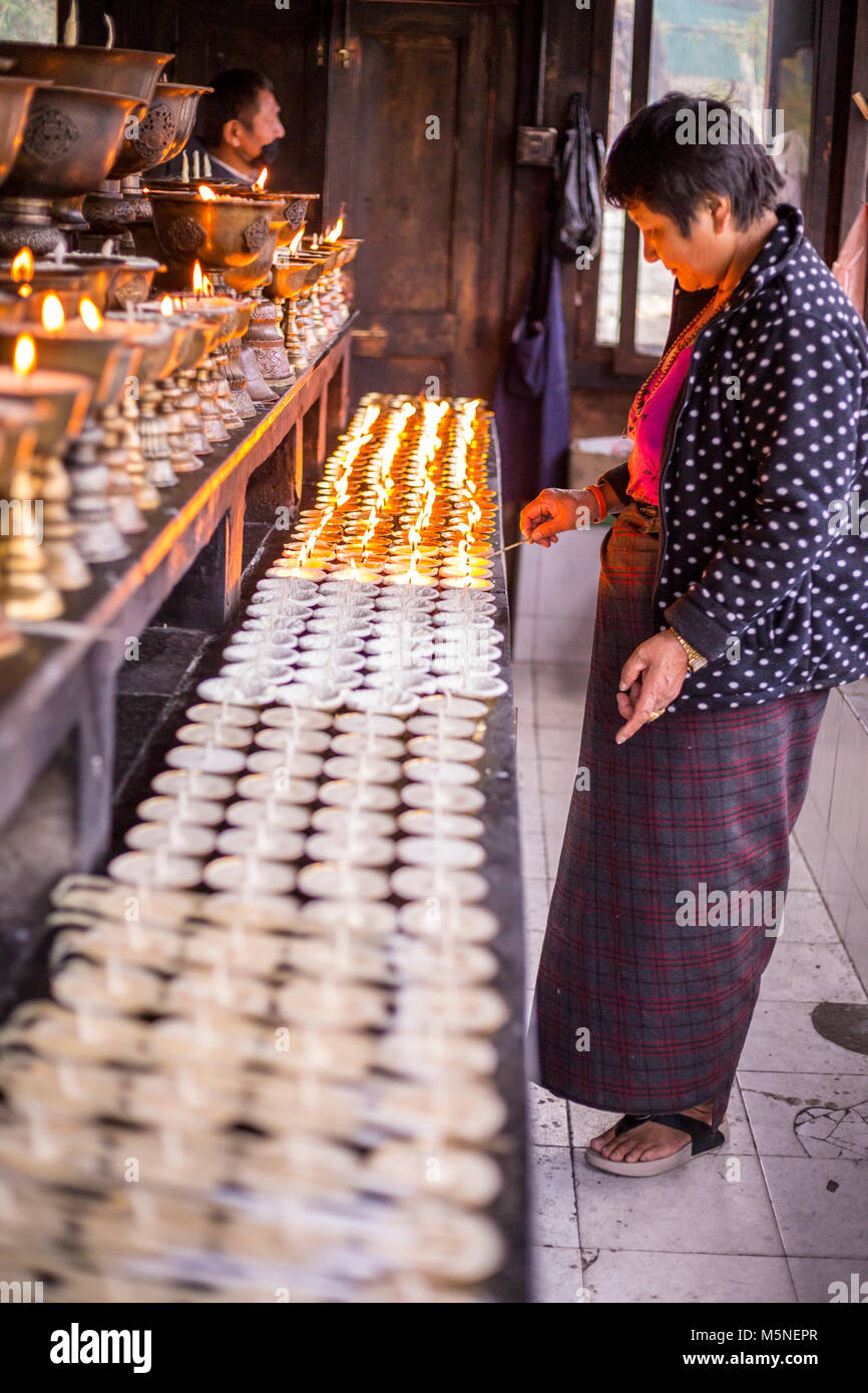 Thimphu, Bhoutan. Femme allumant une bougie à un culte au National Memorial chorten. Banque D'Images