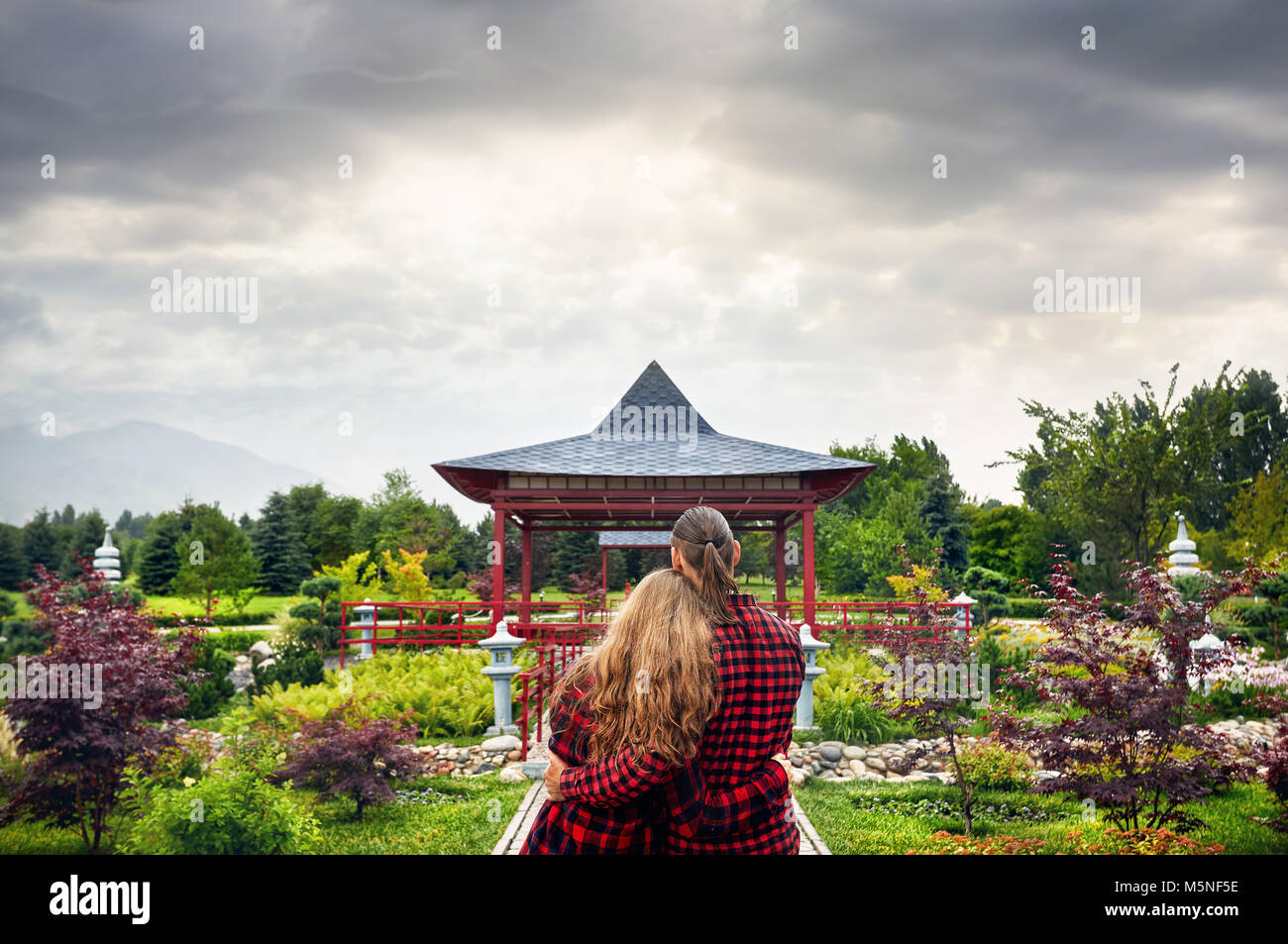 Jeune couple en rouge vérifié shirts hugging et à la recherche à la Pagode japonaise au jardin couvert Banque D'Images