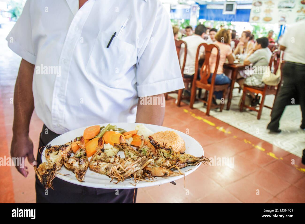 Cancun Mexique,Mexicain,Mercado 28,El Cejas,restaurant à l'intérieur interiorhispanique homme, serveur servant fruits de mer assiette crevettes grillées Banque D'Images