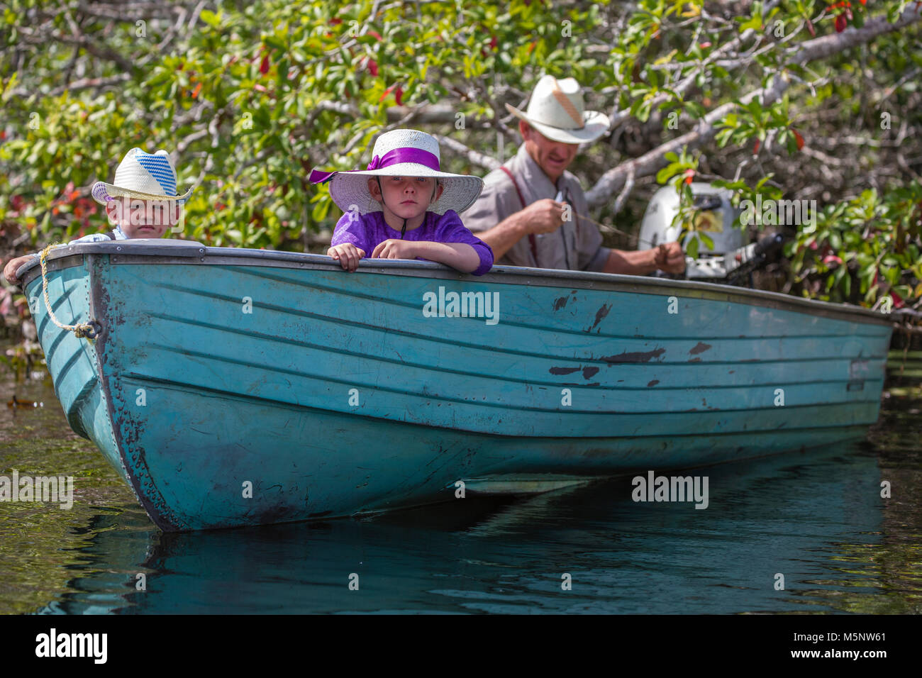 Famille mennonite en bateau sur la rivière New près de Lamanai, Belize Banque D'Images