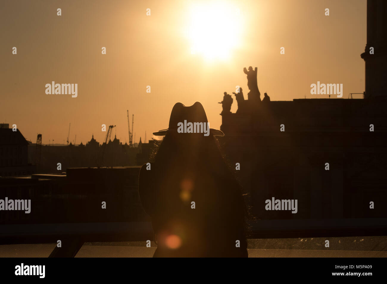 Londres, Royaume-Uni. 25 février 2018. Abeautiful coucher du soleil, le début du coucher de soleil vu de la terrasse du toit d'un nouveau changement. Visiteur dans un chapeau en tenant vos autoportraits dans le coucher du soleil. Credit : Carol Moir/Alamy Live News. Banque D'Images