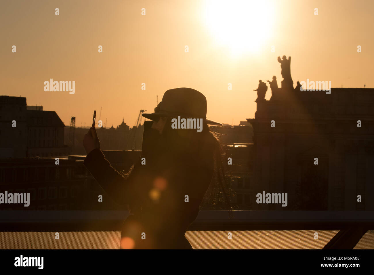 Londres, Royaume-Uni. 25 février 2018. Un beau coucher du soleil, le début du coucher de soleil vu de la terrasse du toit d'un nouveau changement. Visiteur dans un chapeau en tenant vos autoportraits dans le coucher du soleil. Credit : Carol Moir/Alamy Live News. Banque D'Images