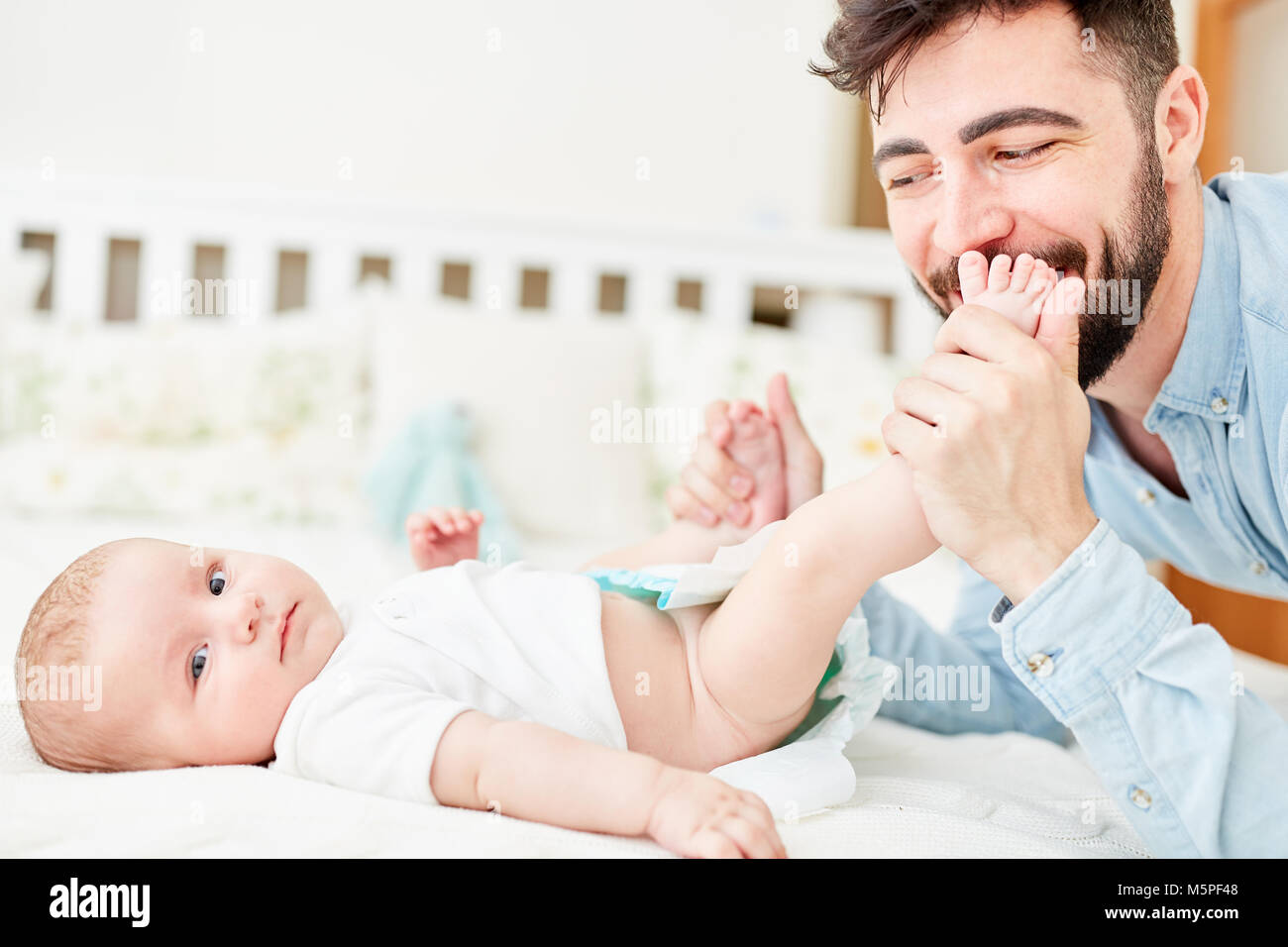 Jeune homme comme un heureux père change les couches de son bébé Banque D'Images