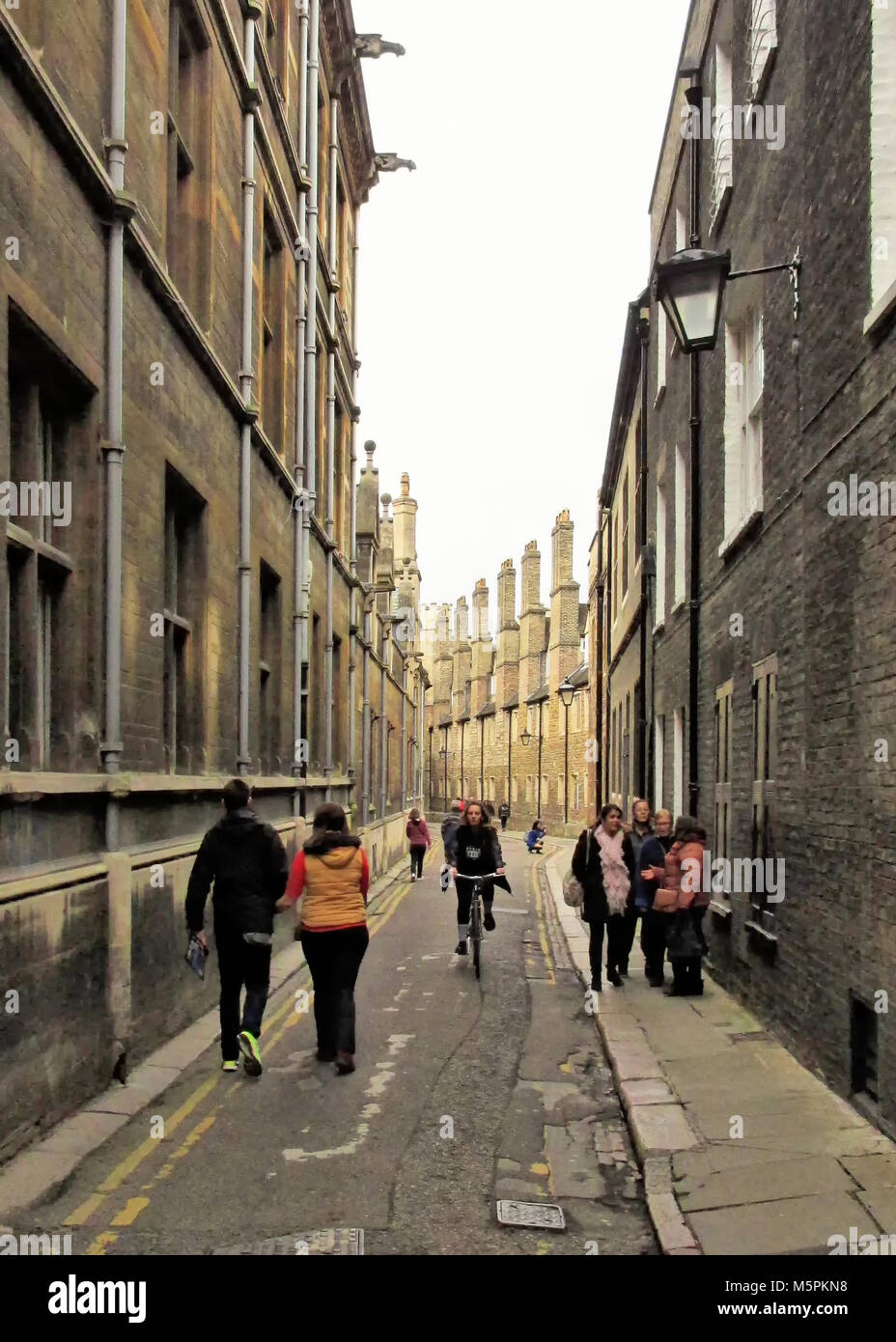 Les piétons et les cyclistes sur une rue étroite à Cambridge, Royaume-Uni. Banque D'Images