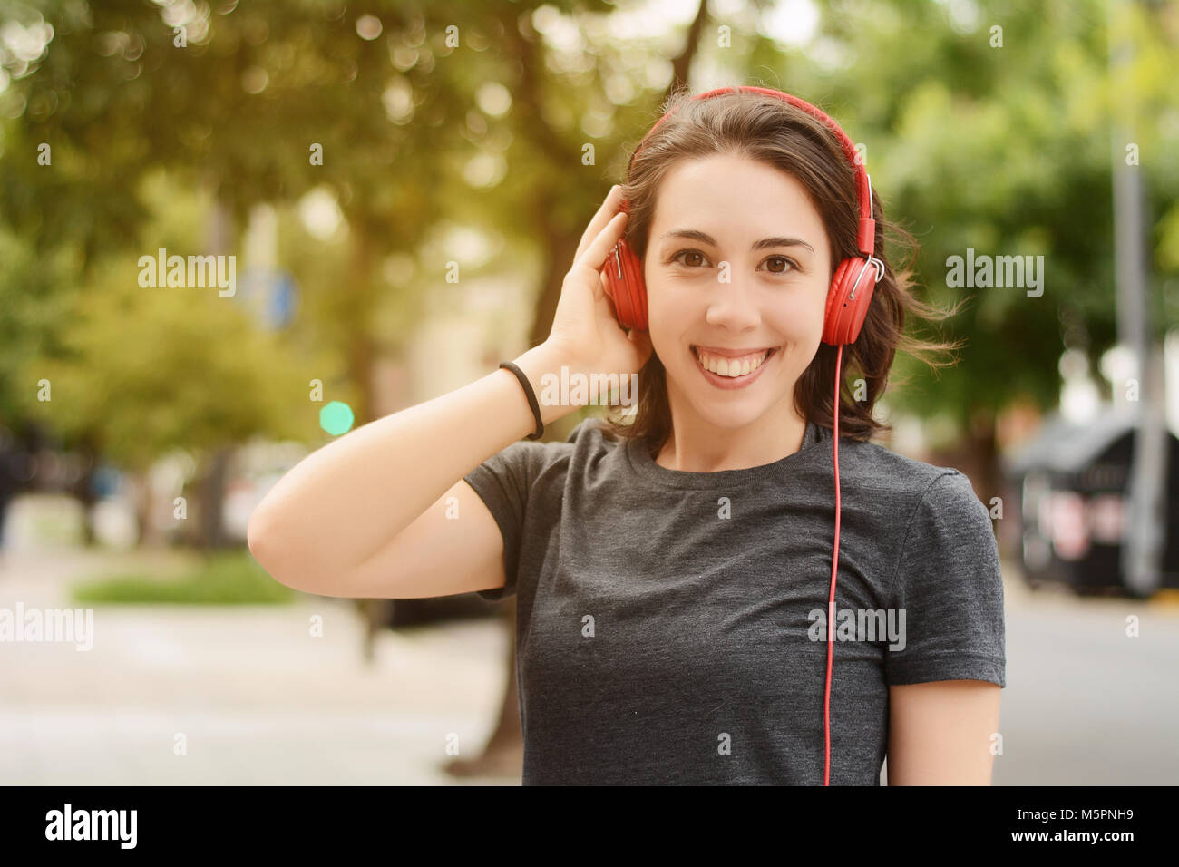 Portrait of young Beautiful woman with red headphones listening music. À l'extérieur. Concept urbain. Banque D'Images