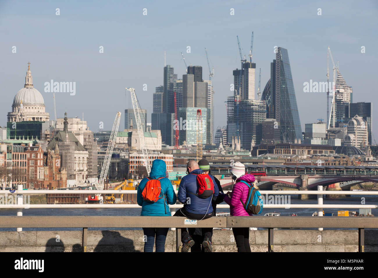 Les touristes habillés de vêtements d'hiver par une froide journée claire, s'arrêter pour admirer la vue de Waterloo Pont sur le gratte-ciel du centre-ville de London, UK Banque D'Images