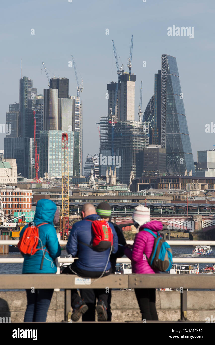 Les touristes habillés de vêtements d'hiver par une froide journée claire, s'arrêter pour admirer la vue de Waterloo Pont sur le gratte-ciel du centre-ville de London, UK Banque D'Images