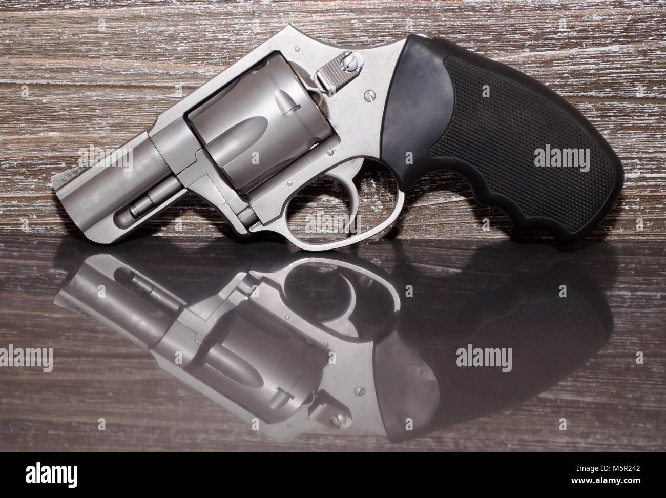 Un revolver Magnum 357 acier inoxydable sur une surface réfléchissante avec un fond de bois Banque D'Images