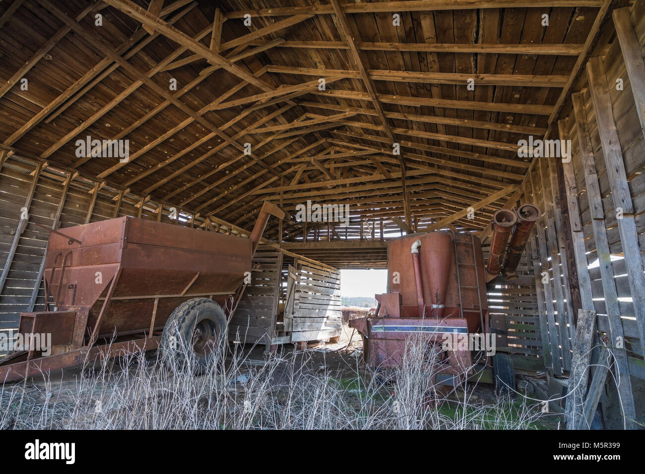 À l'intérieur d'une vieille grange, en plein air. Stocké à l'intérieur est vieux matériel agricole. Banque D'Images