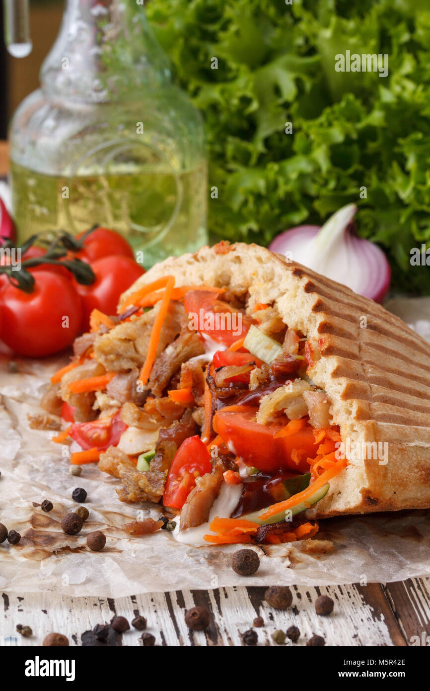 Un plat de pain pita farci de viande grillée, puis la viande hachée et des légumes frais. La nature morte sur un fond de bois. Banque D'Images