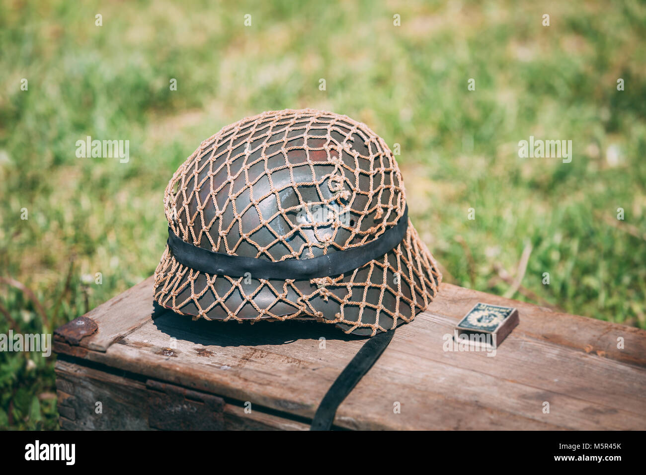Fermer le casque de métal de soldat d'infanterie de la Wehrmacht, les Forces armées de l'Allemagne nazie durant la Seconde Guerre mondiale, située sur l'ancienne boîte en bois sur le Vert Gr Banque D'Images