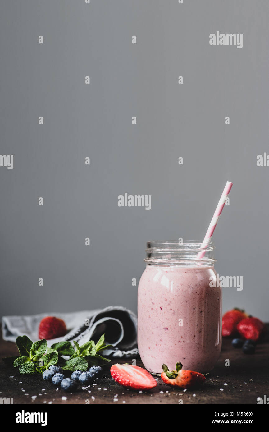 Smoothie rose strawbery en pot avec paille sur fond gris. L'espace de copie de texte, de la tonique de l'image. Mode de vie sain, une alimentation saine notion Banque D'Images