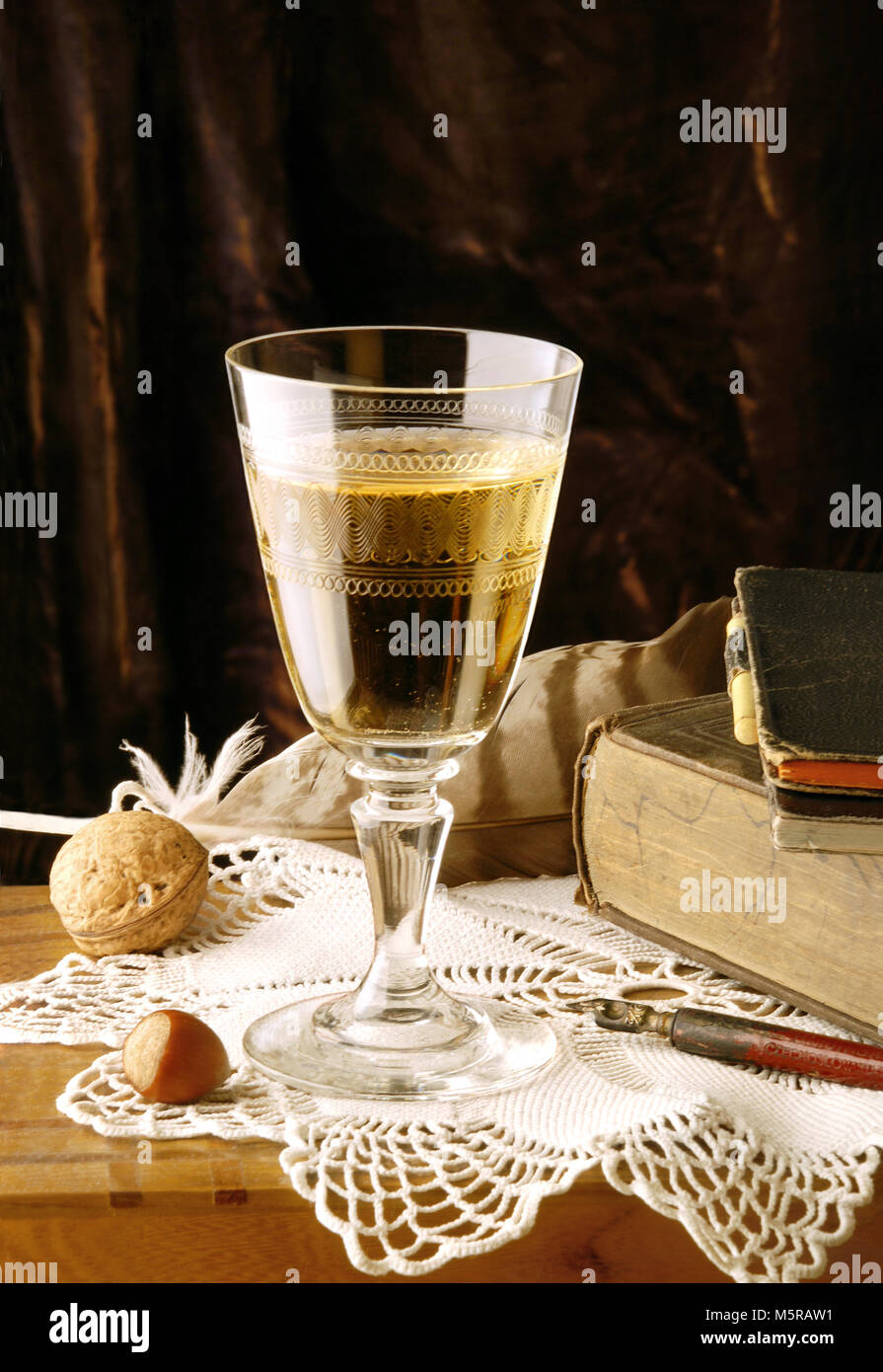 Vintage Nature morte avec verre de vin blanc, noix, livre, plume et plumes Banque D'Images