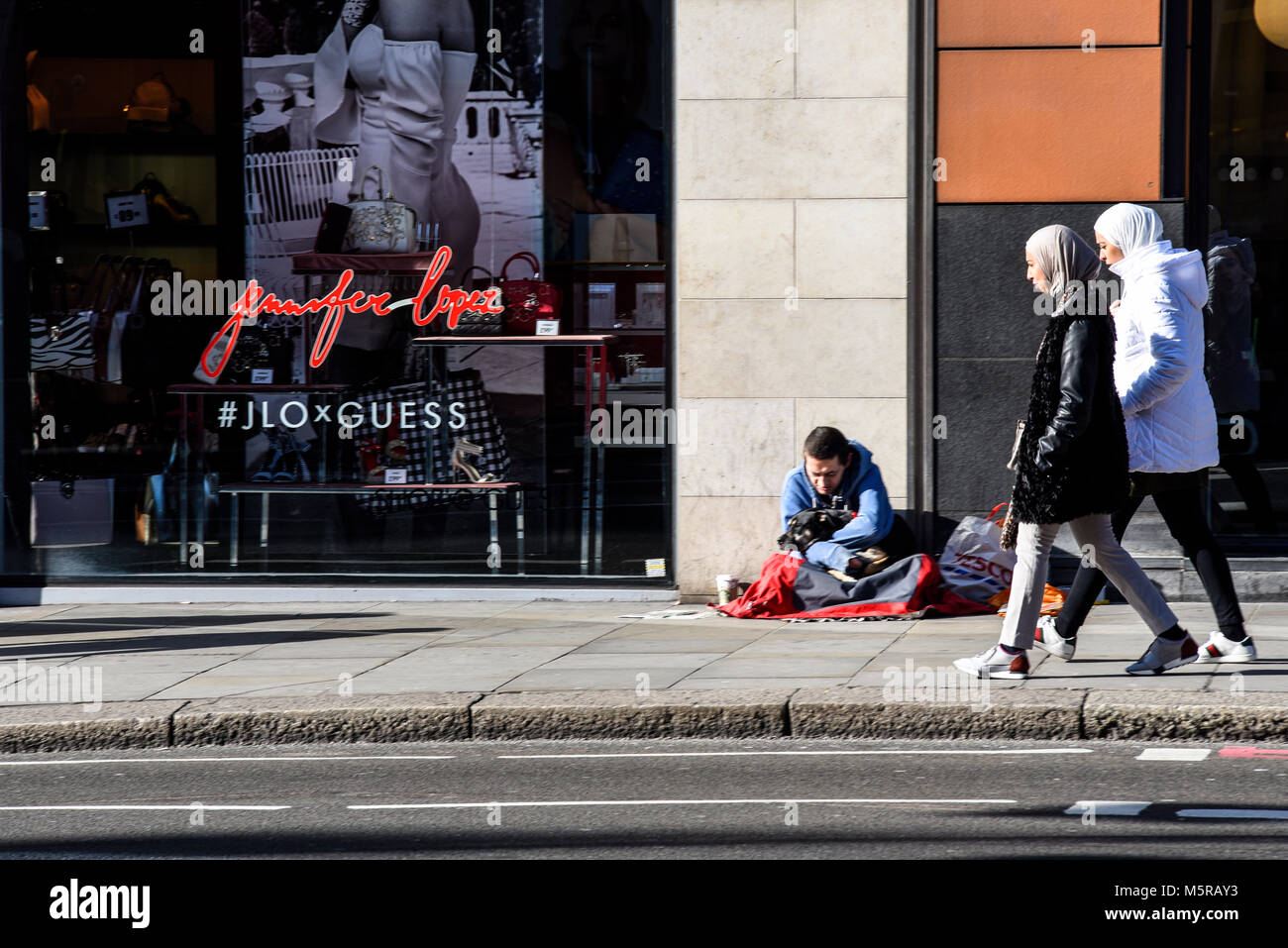 Homme sans abri à Brompton Road, Knightsbridge, Londres dans la rue avec des passants Banque D'Images