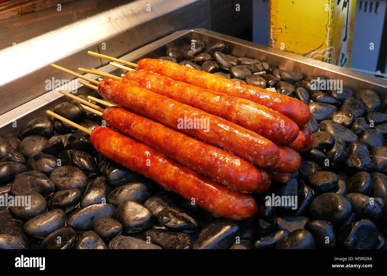 Saucisses taïwanaises savoureux sur des bâtons sur Black lava rock grill Banque D'Images
