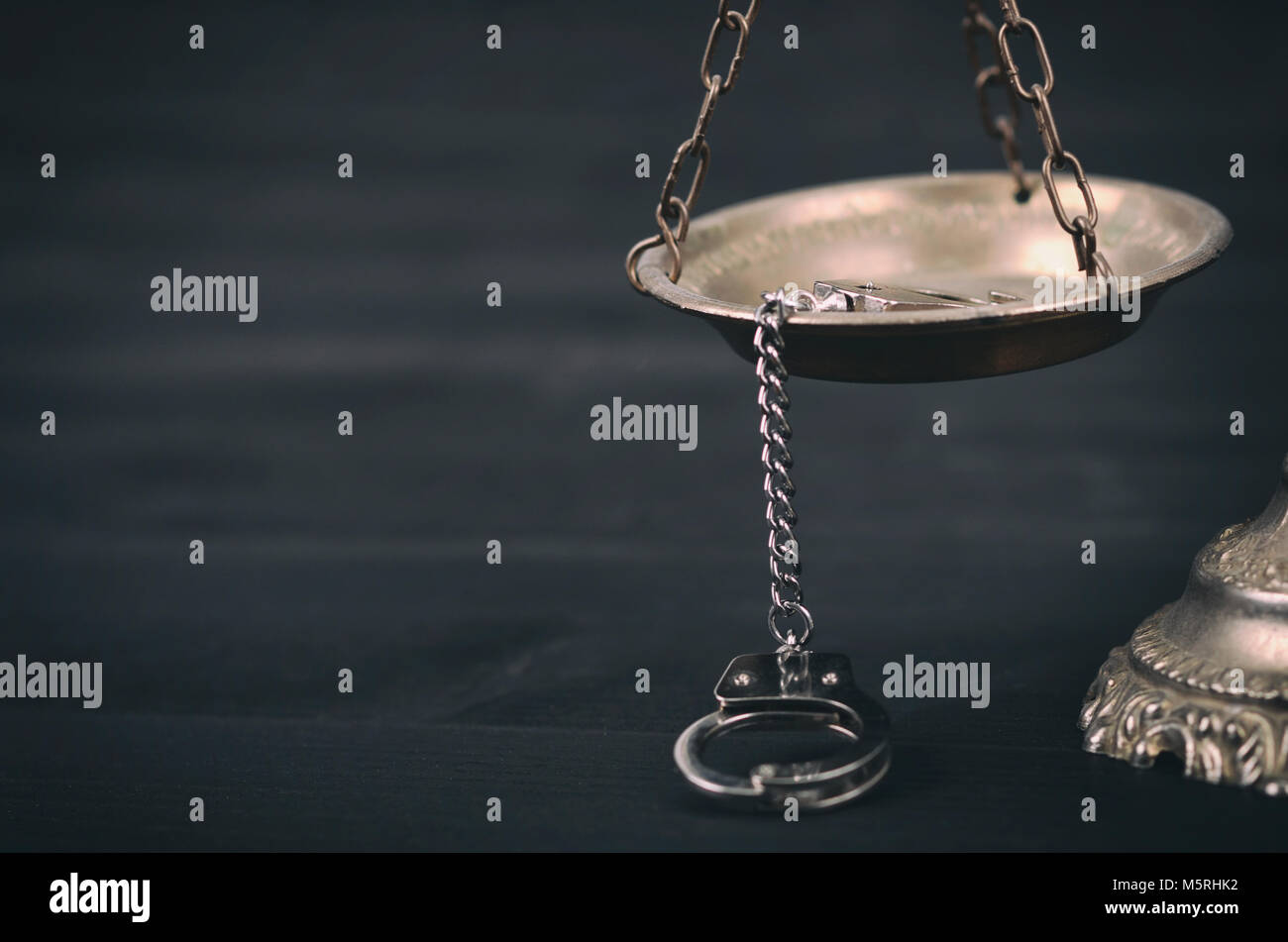 La loi et la justice, la légalité concept, balance de la Justice et des menottes sur un fond de bois noir. Banque D'Images