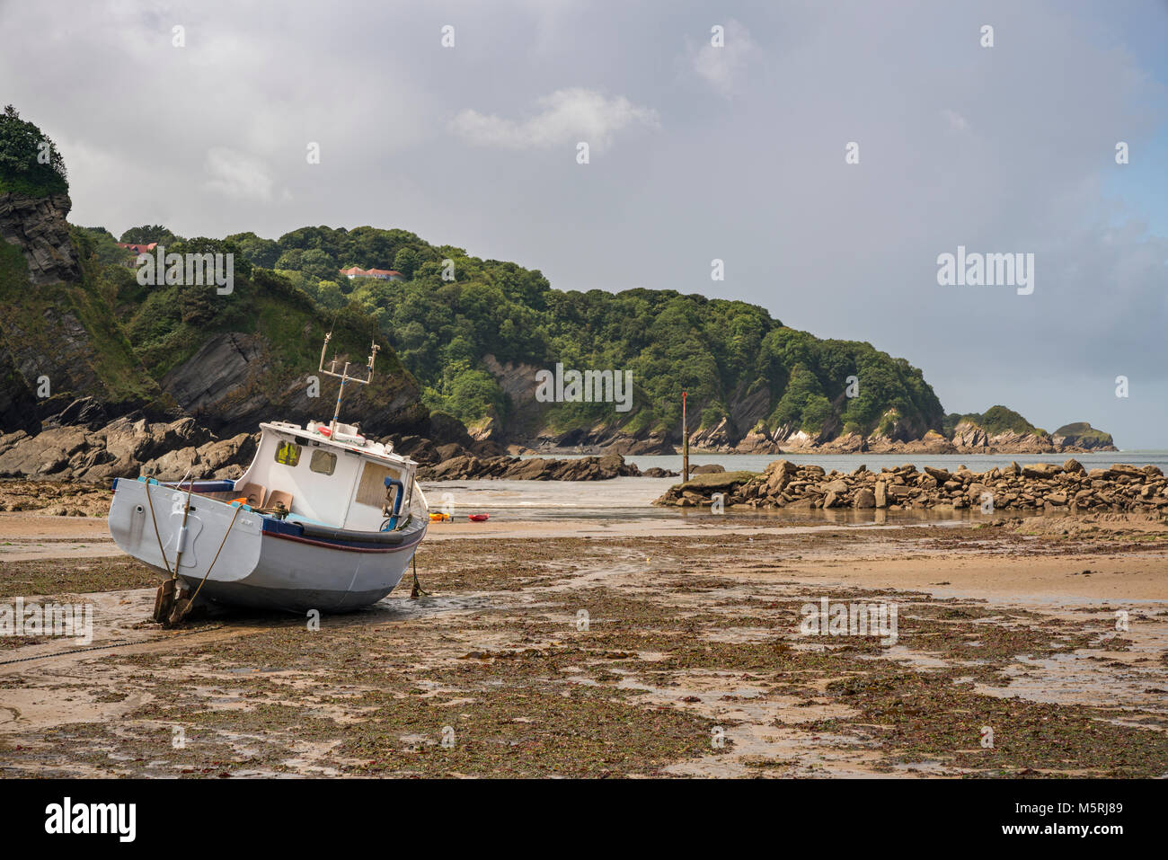 Un bateau de pêche à marée basse sur la plage, dans le port naturel baie abritée de Combe Martin, un village côtier sur la côte nord du Devon à environ 4 mile Banque D'Images