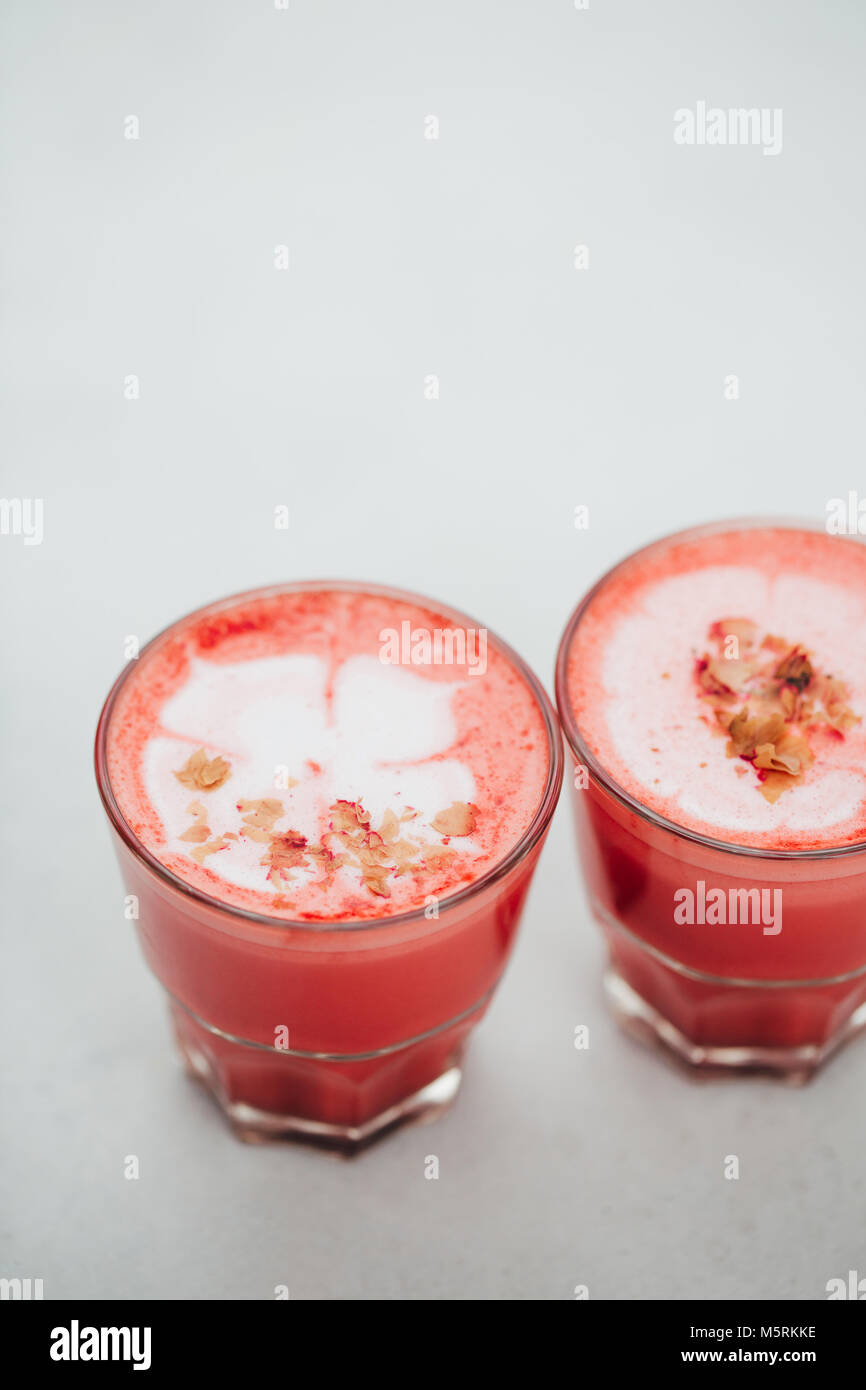 Deux lattes de betterave à la mode avec latte art et pétales de fleurs sur la mousse. Banque D'Images