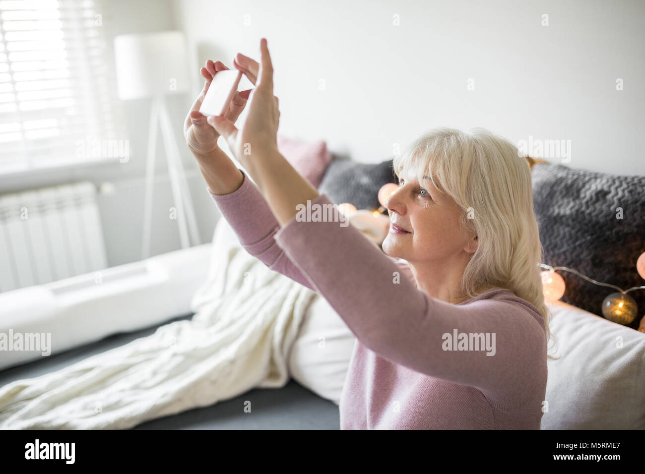 Side portrait of happy senior lady prenant elle-même photo par mobile Banque D'Images