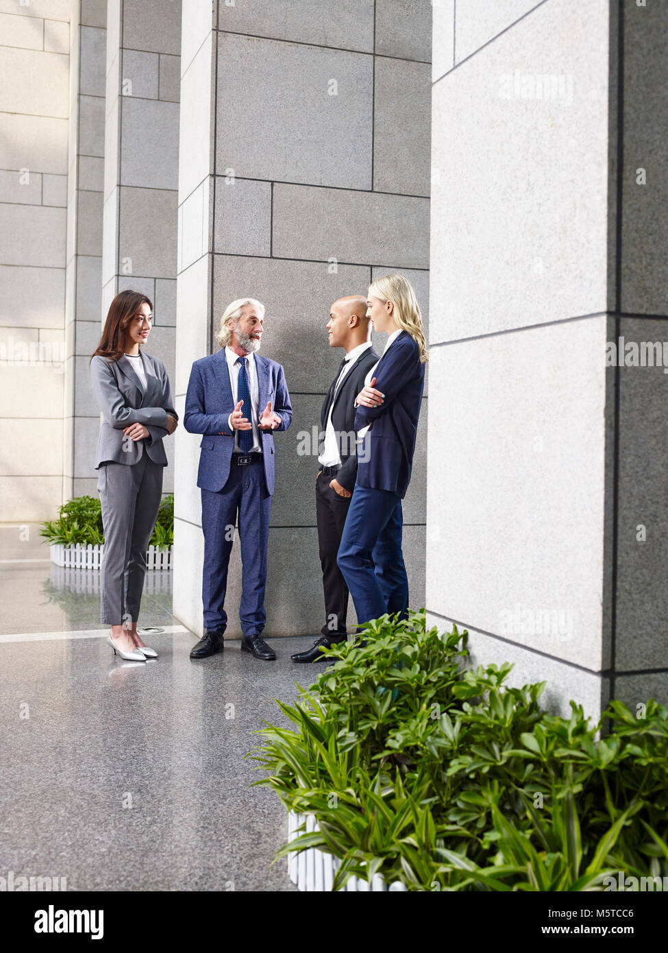 Force multinationale et multiethnique, business people standing parler chat dans hall d'immeuble de bureaux modernes. Banque D'Images