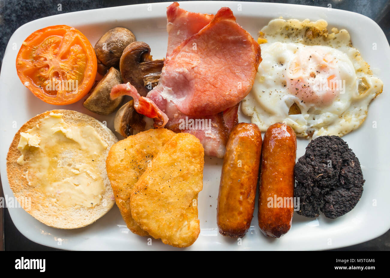 Le petit déjeuner anglais complet en œuf frit, bacon, haricots blancs, blanc muffin, boudin noir