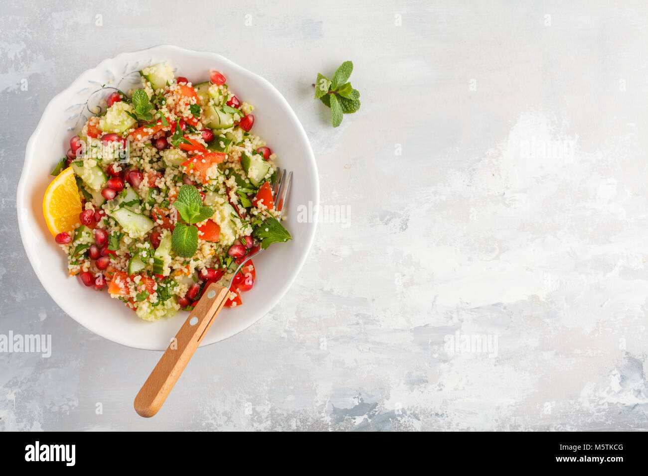 Taboulé salade avec tomates, concombres, couscous, menthe et grenade, vue du dessus. Traditionnels ou plat arabe. Banque D'Images