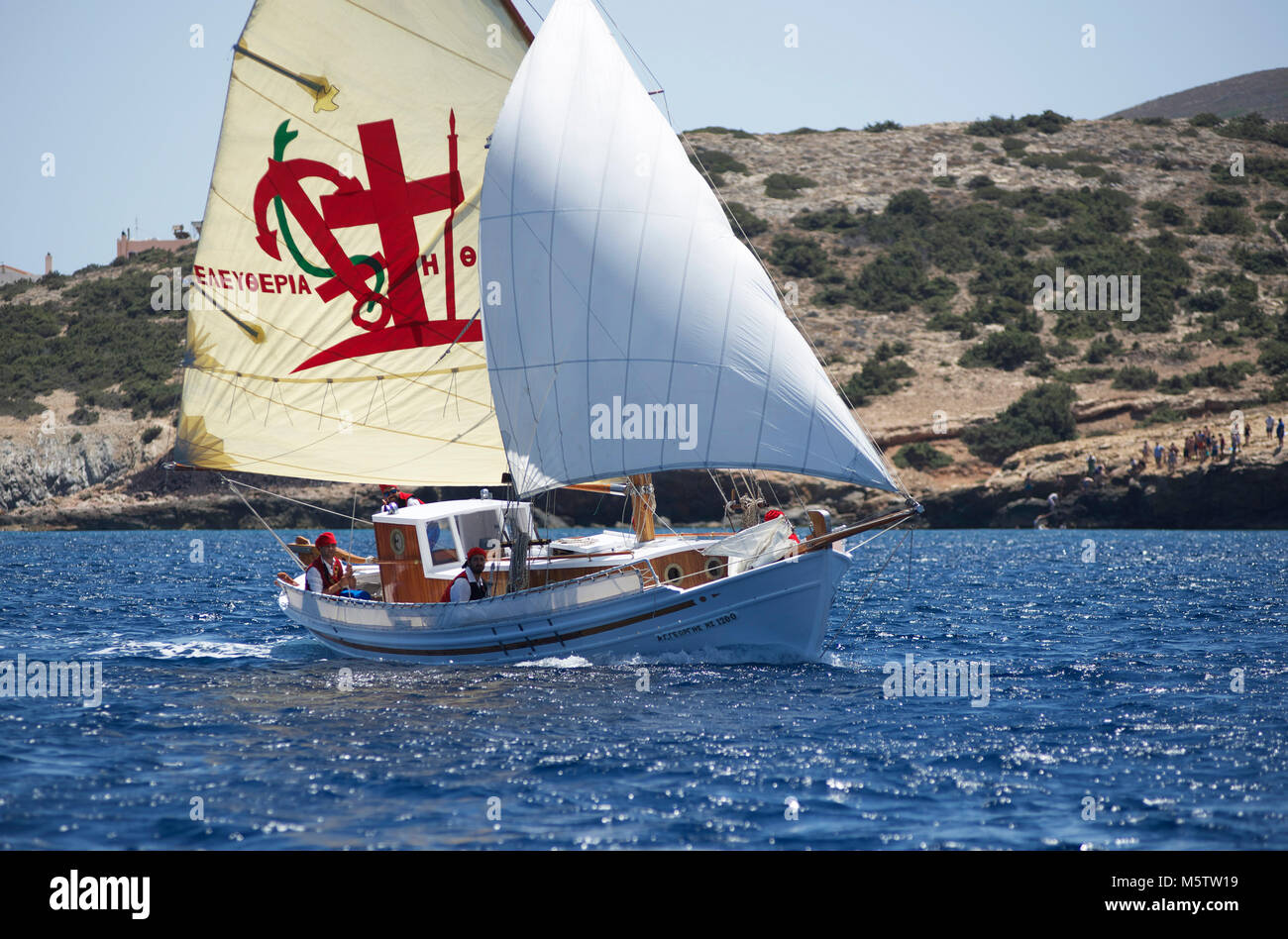 Bateau de pêche traditionnel grec à Agios Georgios off Syros Cyclades durant la Classic Yacht Race. L'équipage portent costume tradition. Banque D'Images