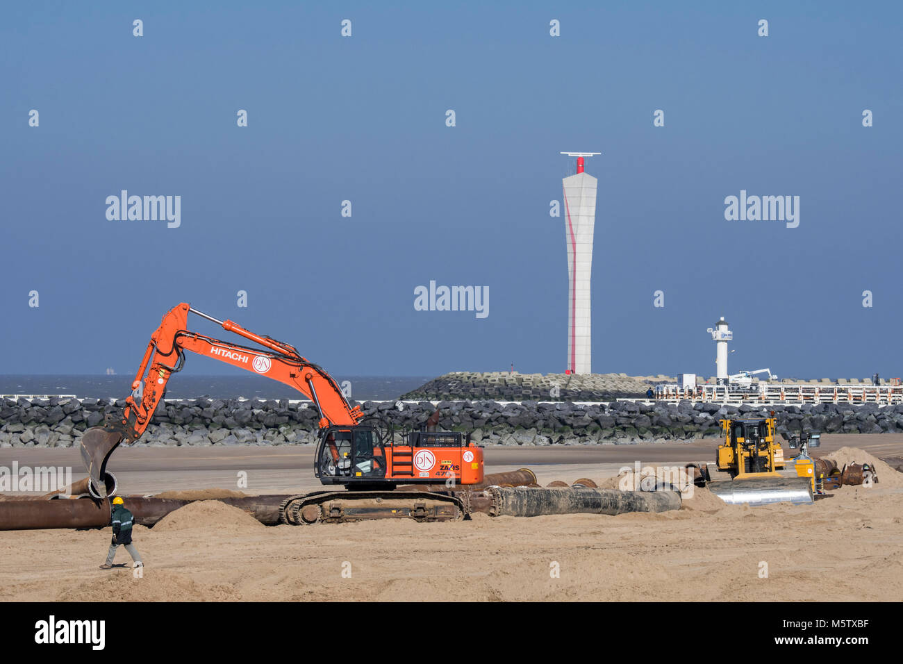 Pelle hydraulique bulldozer et l'installation de pipeline au cours de reconstitution des plages de sable / Travaux publics le long de la côte belge à Ostende, Belgique Banque D'Images
