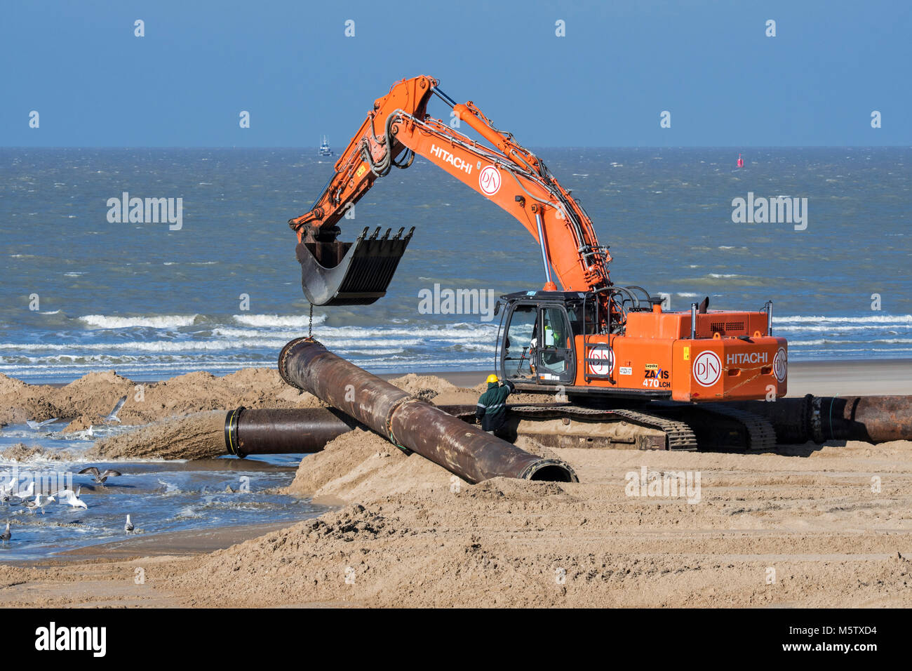 Excavateur hydraulique installation de pipeline au cours de reconstitution des plages de sable / Travaux publics le long de la côte belge à Ostende, Belgique Banque D'Images