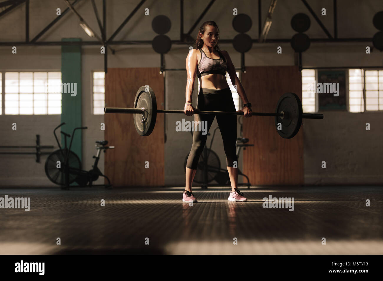 Convient jeune athlète féminine soulevant des poids lourds. modele de remise en forme effectuant des exercices de poids au gymnase. Banque D'Images